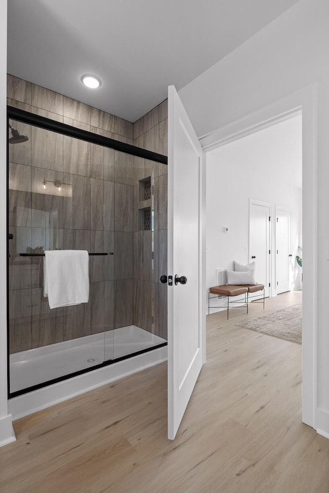 bathroom featuring wood finished floors and a shower stall