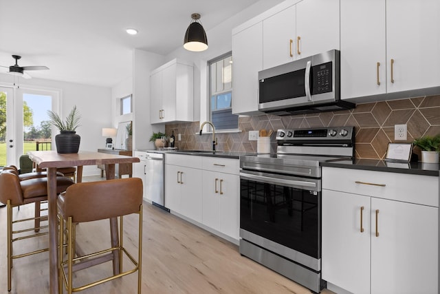 kitchen featuring appliances with stainless steel finishes, dark countertops, white cabinets, and a sink