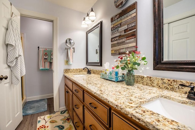 bathroom featuring double vanity, baseboards, a sink, and wood finished floors