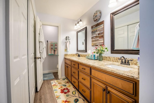 full bathroom featuring double vanity, toilet, a sink, and wood finished floors