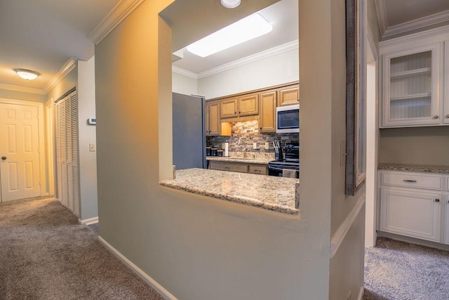 kitchen with stainless steel appliances, dark colored carpet, crown molding, white cabinetry, and a sink