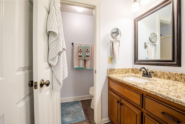 bathroom featuring wood finished floors, vanity, toilet, and baseboards