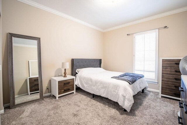 bedroom with ornamental molding, carpet flooring, and baseboards