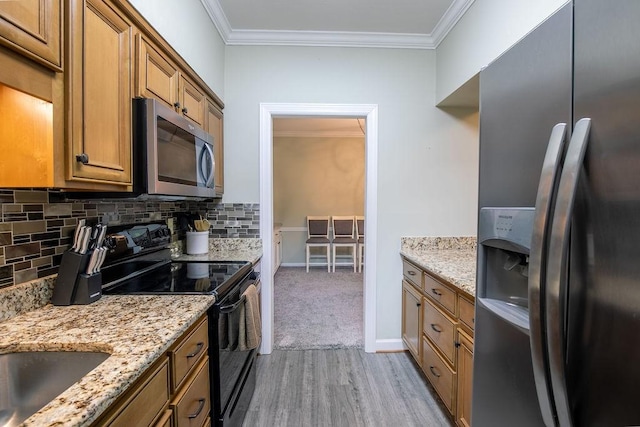 kitchen with appliances with stainless steel finishes, brown cabinets, ornamental molding, and light stone countertops