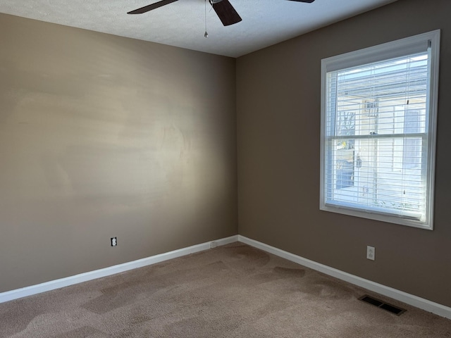 carpeted spare room featuring baseboards, visible vents, and a ceiling fan