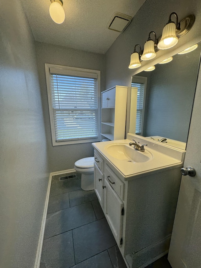 half bath with visible vents, toilet, vanity, baseboards, and tile patterned floors