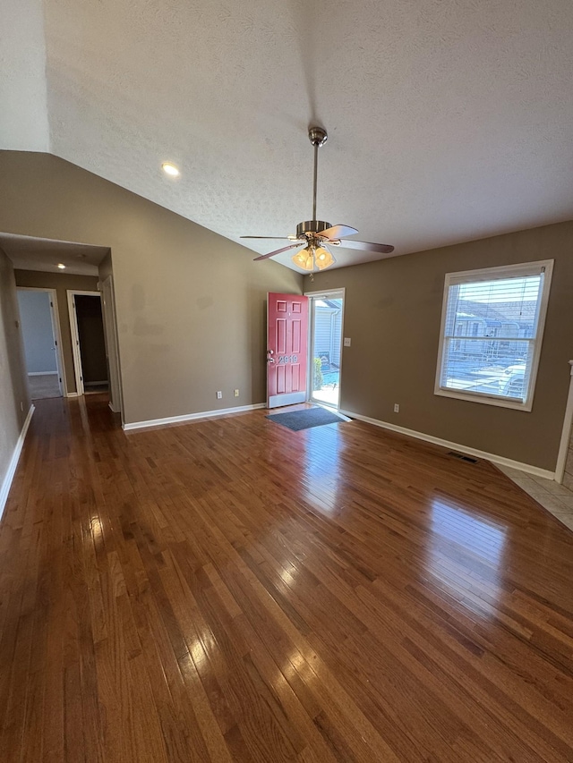 interior space featuring dark wood-type flooring, lofted ceiling, a healthy amount of sunlight, and visible vents