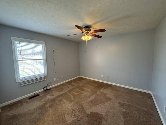 spare room with visible vents, baseboards, a ceiling fan, carpet, and a textured ceiling