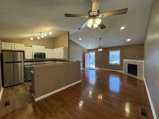 kitchen with lofted ceiling, visible vents, appliances with stainless steel finishes, open floor plan, and white cabinetry