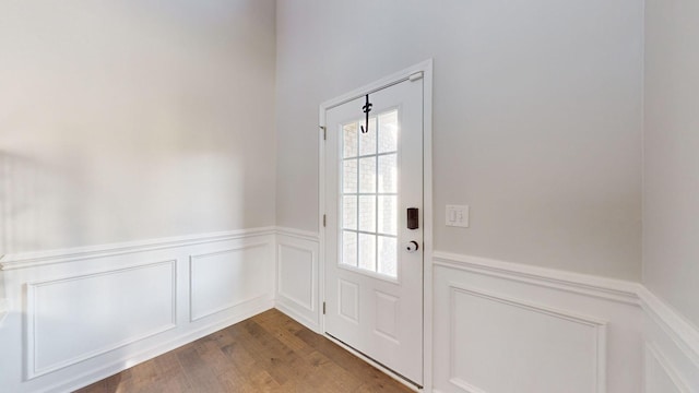 doorway with dark wood-style flooring and wainscoting