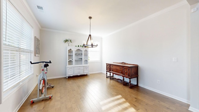 interior space featuring ornamental molding, a notable chandelier, baseboards, and wood finished floors