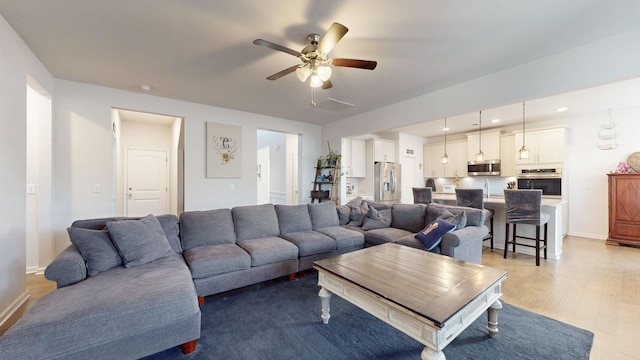 living room with light wood finished floors, recessed lighting, a ceiling fan, and baseboards