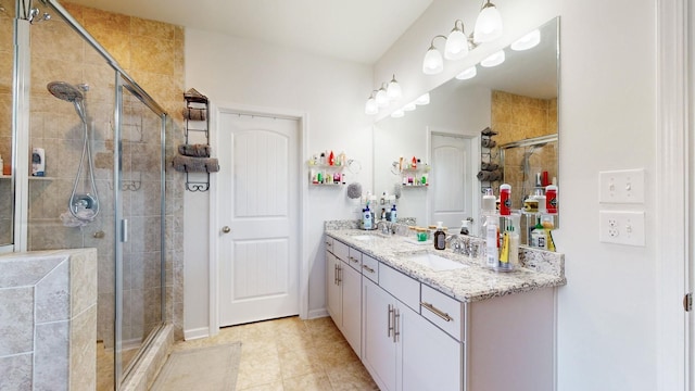 full bath featuring double vanity, a stall shower, baseboards, and a sink