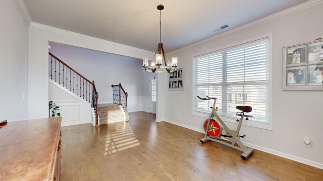 exercise area with an inviting chandelier, crown molding, visible vents, and wood finished floors