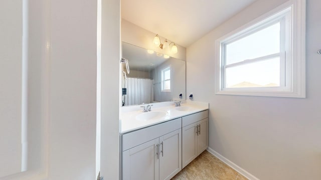 full bathroom featuring double vanity, baseboards, a sink, and tile patterned floors