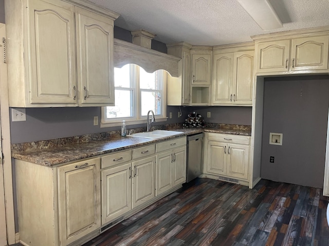 kitchen with dark countertops, a sink, dark wood-style flooring, and stainless steel dishwasher