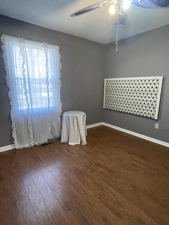 empty room featuring dark wood-style flooring and baseboards
