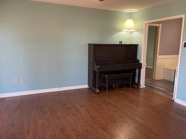 living area with dark wood-style flooring, a textured ceiling, and baseboards