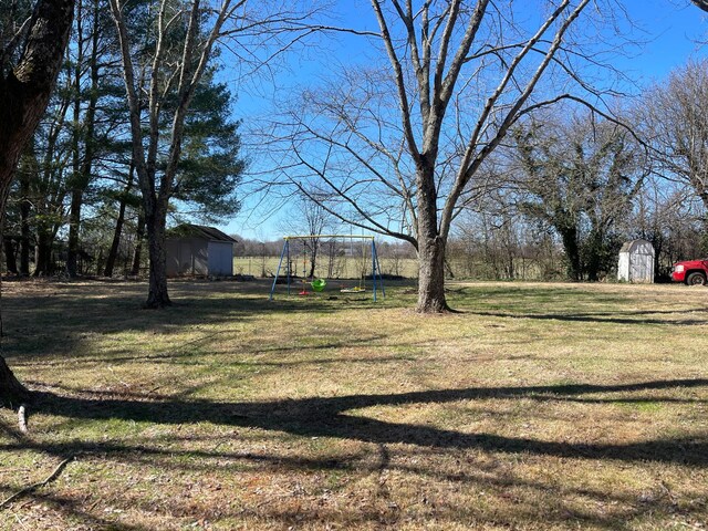 view of yard featuring a storage shed, a playground, and an outbuilding