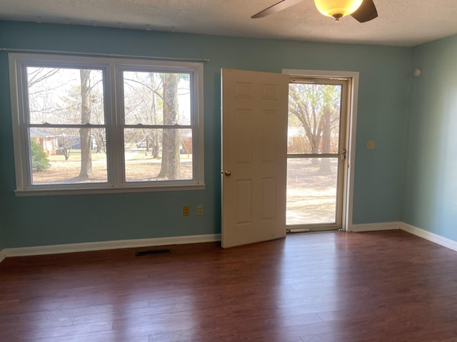 spare room with a textured ceiling, ceiling fan, dark wood-style flooring, and baseboards