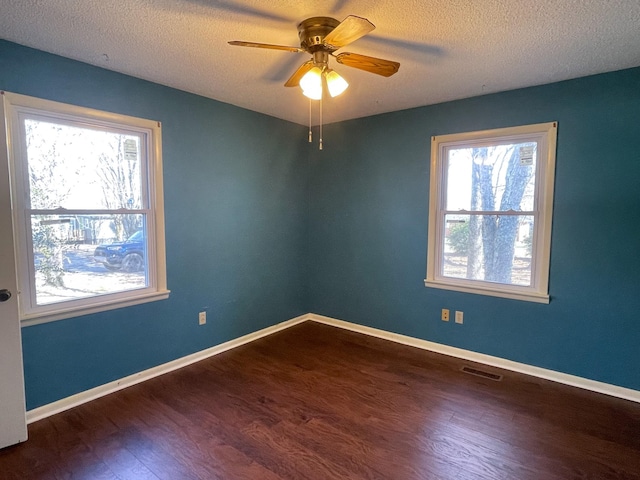 empty room featuring baseboards, visible vents, ceiling fan, and dark wood-type flooring