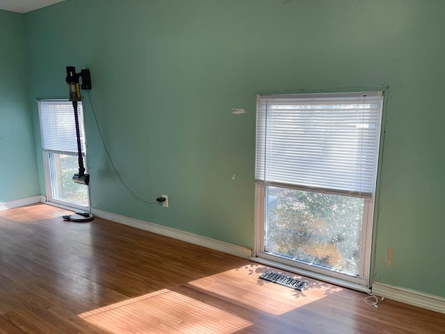 unfurnished room with visible vents, baseboards, and wood finished floors