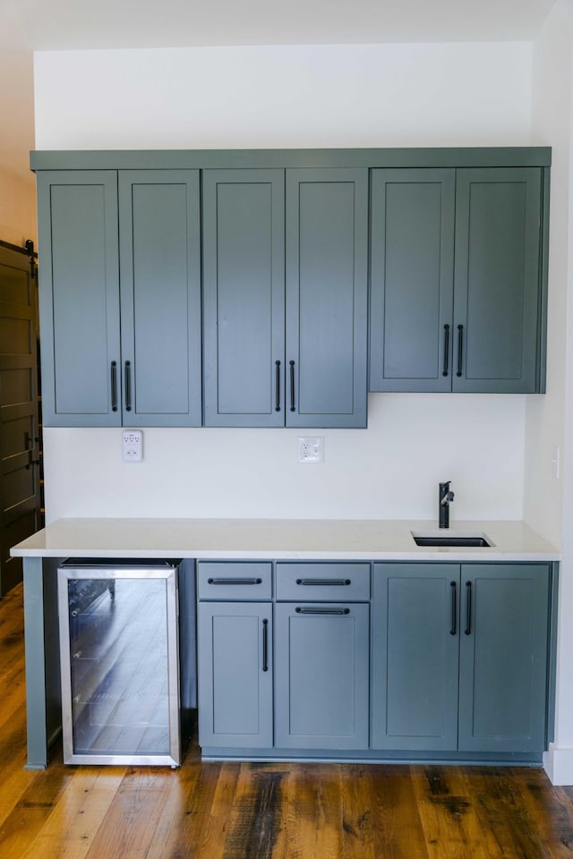 bar with dark wood-style floors, a barn door, wine cooler, and a sink