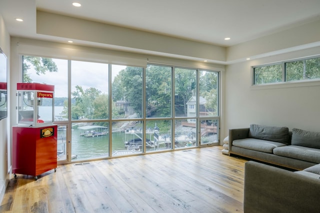 living area featuring a water view, wood finished floors, and recessed lighting