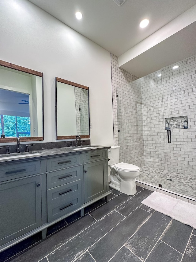 bathroom with double vanity, a stall shower, a sink, and toilet