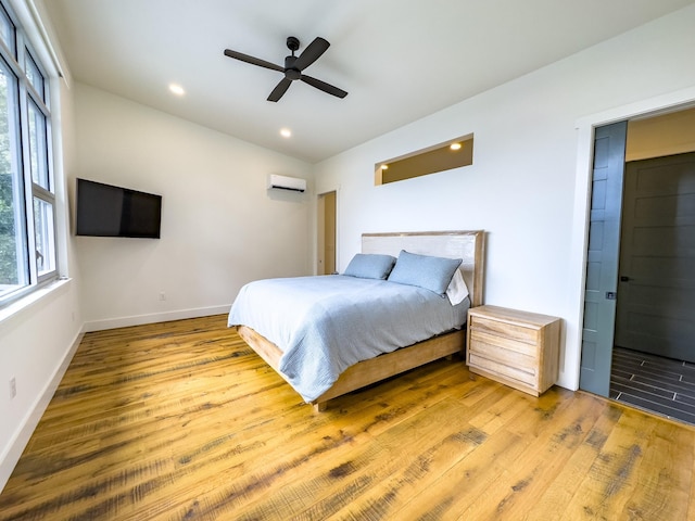 bedroom featuring a wall unit AC, multiple windows, vaulted ceiling, and wood finished floors