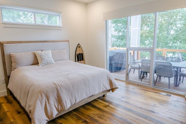 bedroom featuring access to outside, multiple windows, visible vents, and wood finished floors