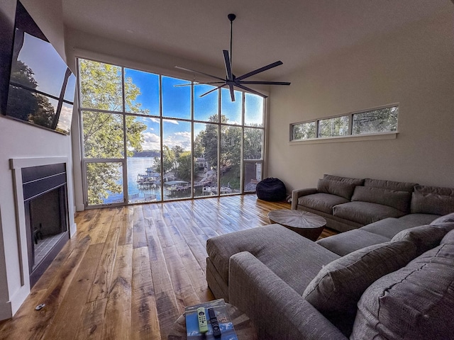 unfurnished living room with ceiling fan, a high ceiling, a fireplace, and wood finished floors