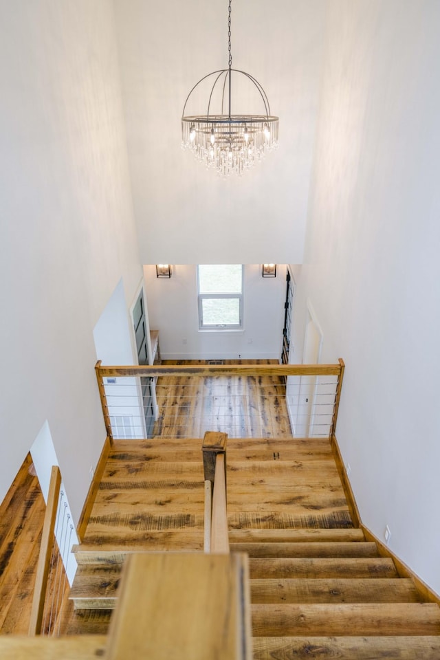 stairs featuring a towering ceiling, an inviting chandelier, and baseboards