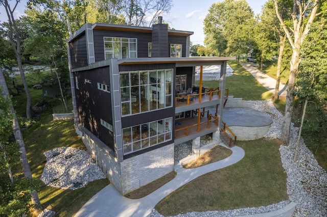 rear view of property with a sunroom, a patio area, a lawn, and a chimney