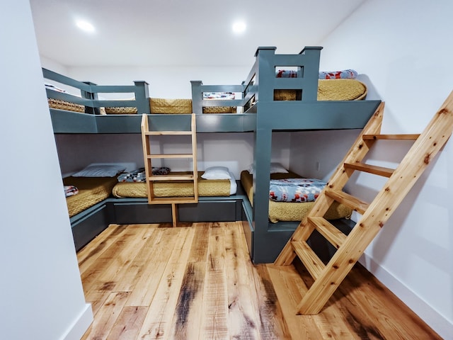 bedroom with baseboards, wood finished floors, and recessed lighting