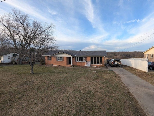 ranch-style home with brick siding, driveway, a front lawn, and fence