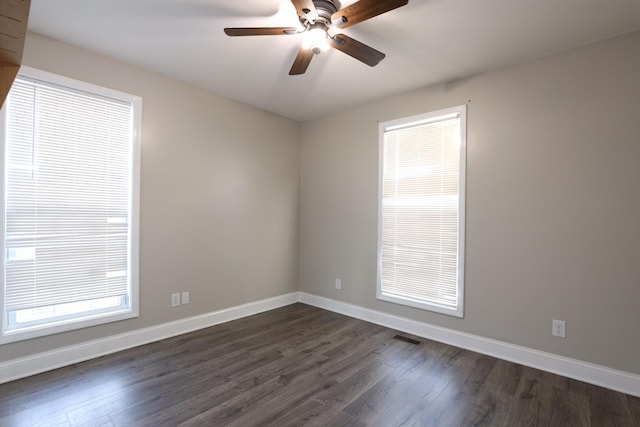 unfurnished room with ceiling fan, dark wood-style flooring, visible vents, and baseboards