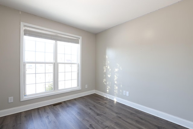 unfurnished room with baseboards, visible vents, and dark wood finished floors