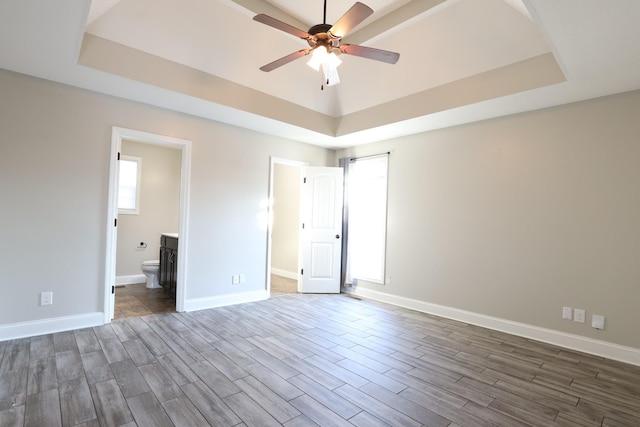 unfurnished bedroom featuring a tray ceiling and dark wood finished floors