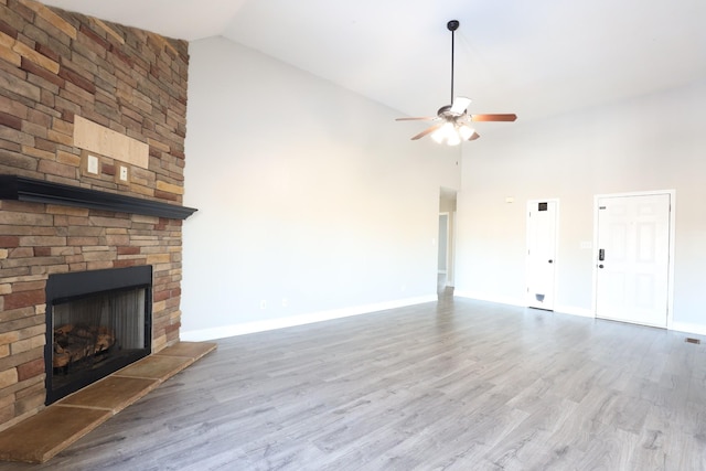 unfurnished living room with a large fireplace, ceiling fan, wood finished floors, and baseboards