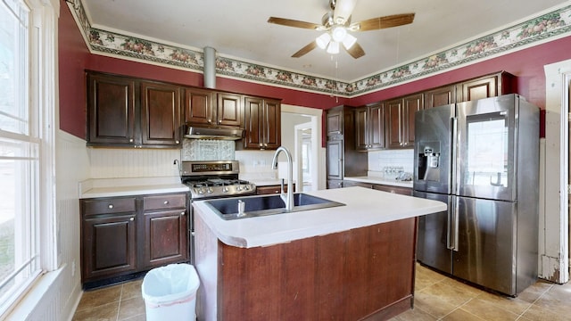 kitchen with under cabinet range hood, stainless steel appliances, a sink, and light countertops