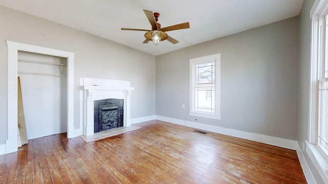 unfurnished living room featuring a fireplace, wood-type flooring, visible vents, ceiling fan, and baseboards