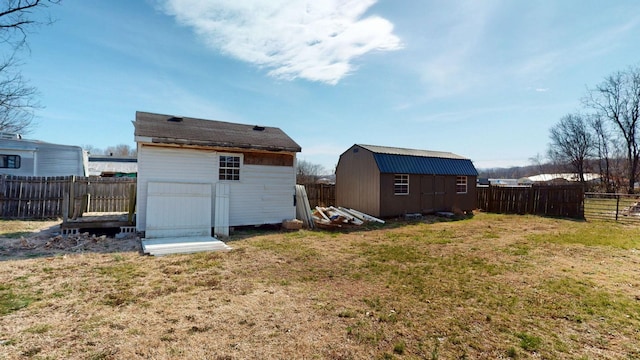 back of house featuring a storage shed, a fenced backyard, a lawn, and an outbuilding