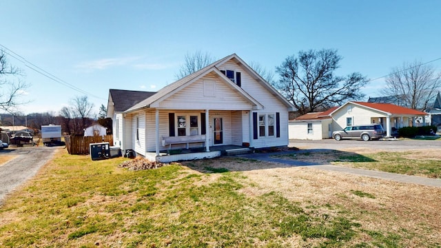 bungalow with covered porch, fence, and a front lawn