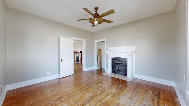 unfurnished living room featuring baseboards, ceiling fan, hardwood / wood-style floors, and a tiled fireplace