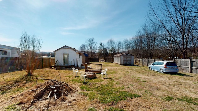 view of yard with an outdoor fire pit, a fenced backyard, and an outdoor structure