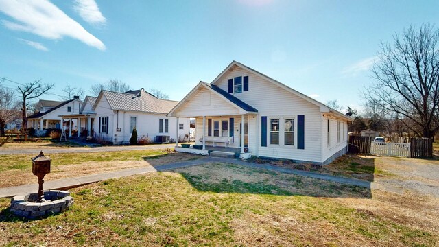 bungalow-style home with covered porch, a front lawn, and fence