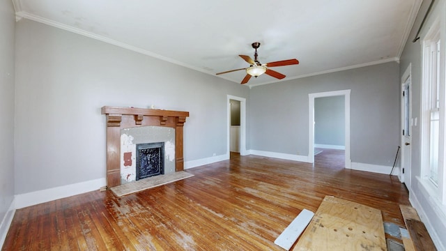 unfurnished living room featuring ceiling fan, hardwood / wood-style flooring, a fireplace, baseboards, and ornamental molding