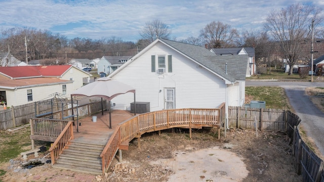 back of house with a deck, central AC unit, roof with shingles, and a fenced backyard