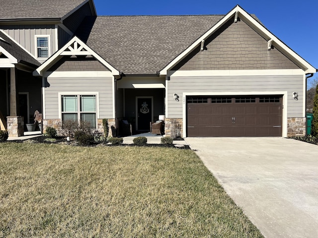 craftsman house featuring a garage, driveway, stone siding, roof with shingles, and a front yard